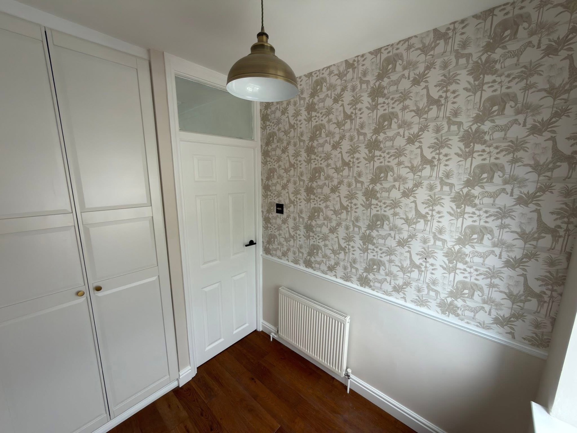 Bedroom with hand-hung patterned wallpaper above a painted dado