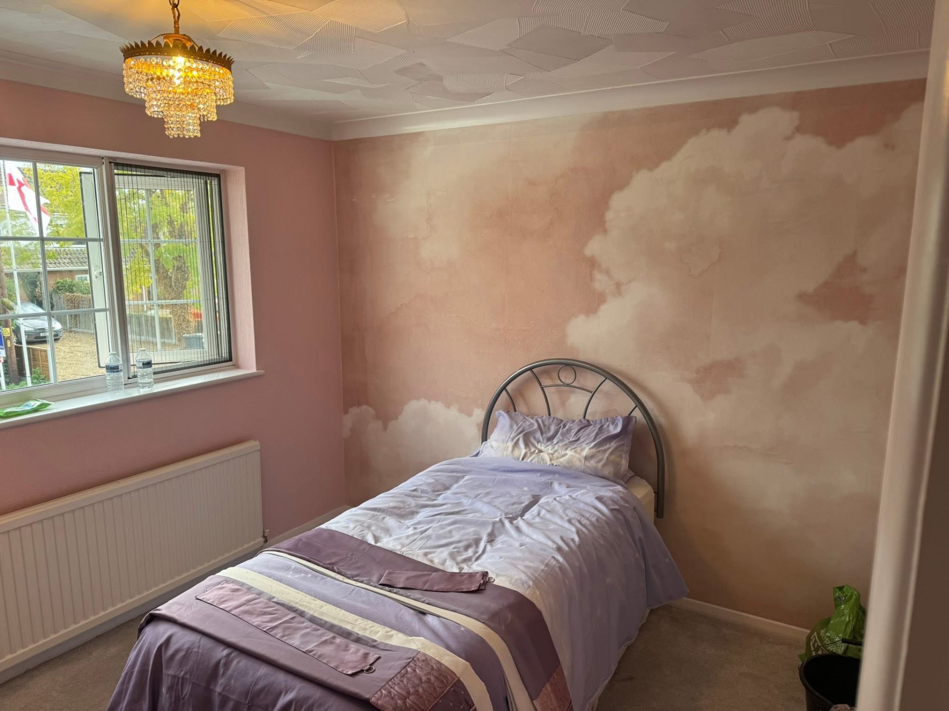 Hand-painted cloud mural on a soft pink bedroom wall