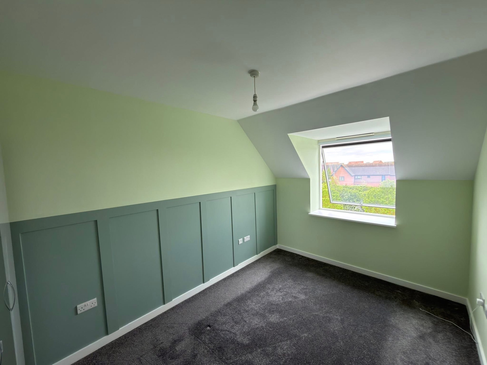 Loft bedroom with bespoke sage green panelling and two-tone walls