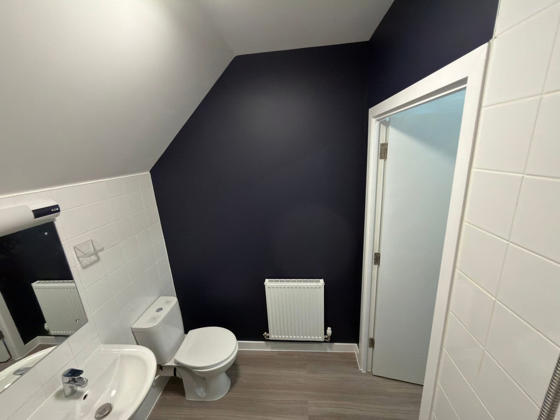 Bathroom with a deep navy feature wall against white tiling
