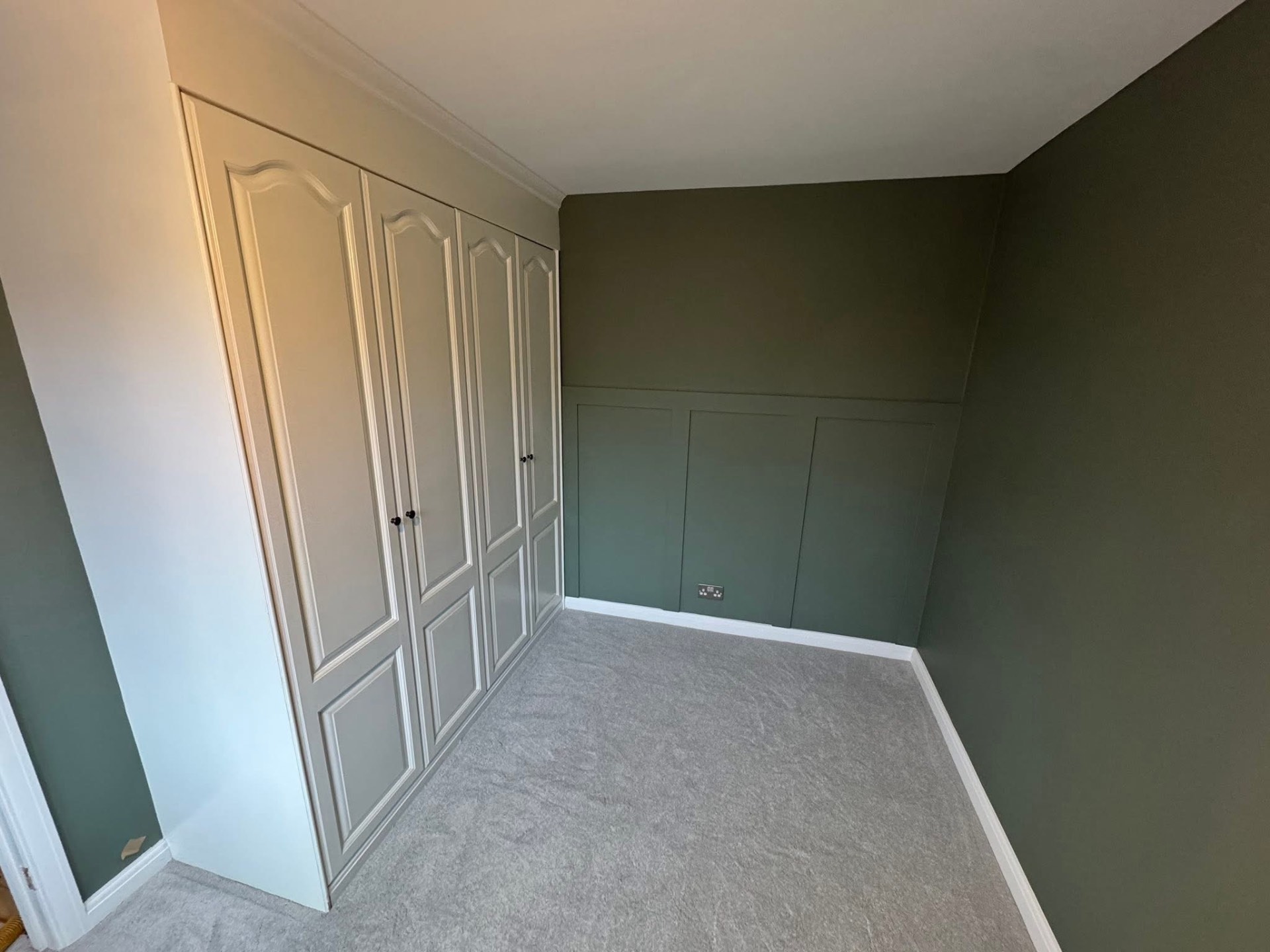 Fitted wardrobes beside a green panelled feature wall